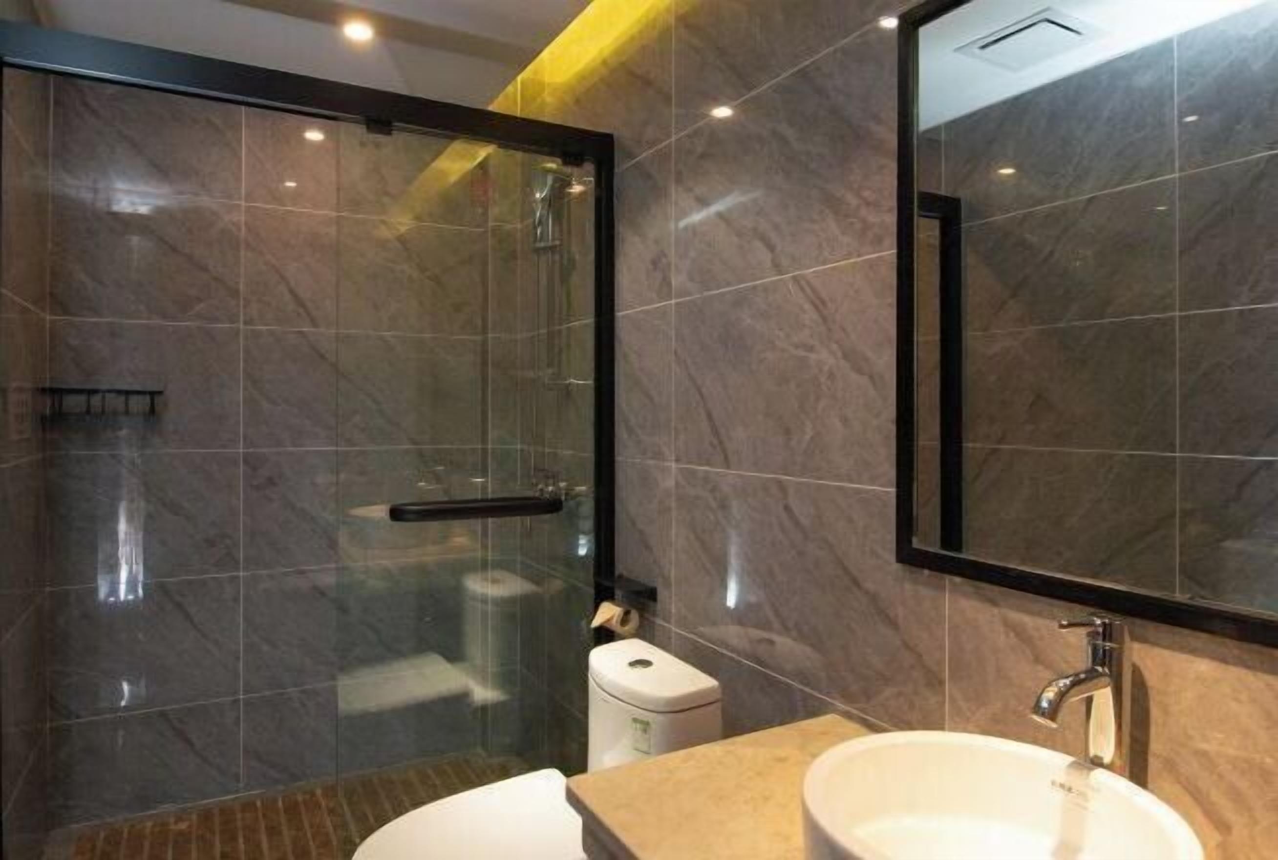 A modern bathroom with a glass-enclosed shower, a white sink, and a marble-tiled wall.