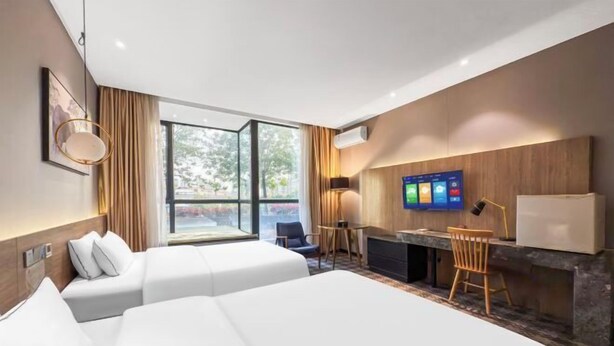 Habitación de hotel con dos camas, un escritorio, televisión y vistas al exterior.