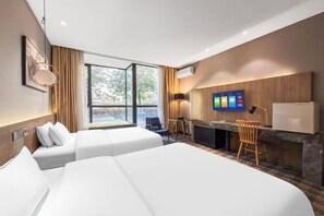 Une chambre d’hôtel avec deux lits, un bureau, une télévision et une vue sur l’extérieur.