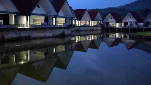 Una hilera de edificios modernos con techos triangulares y agua reflectante al frente.