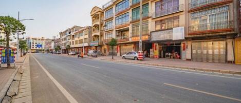 A street with multi-story buildings, storefronts, and parked cars.
