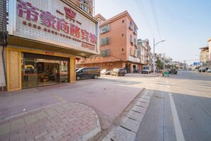 A street view with a building featuring a storefront with a sign, a sidewalk, and parked cars. - Fengkai Dihao Business Hotel (Fengkai)