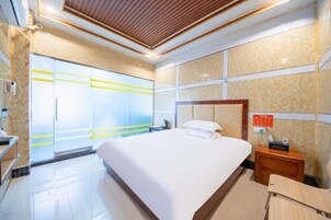 A hotel room with a large bed, a wooden headboard, a bedside table with a phone, and a wardrobe with sliding doors.