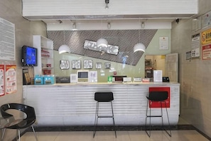 A reception area with a counter, two bar stools, a television, and various items on the counter.
