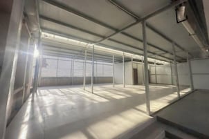 Una habitación amplia de estilo industrial, con vigas metálicas y techo alto.