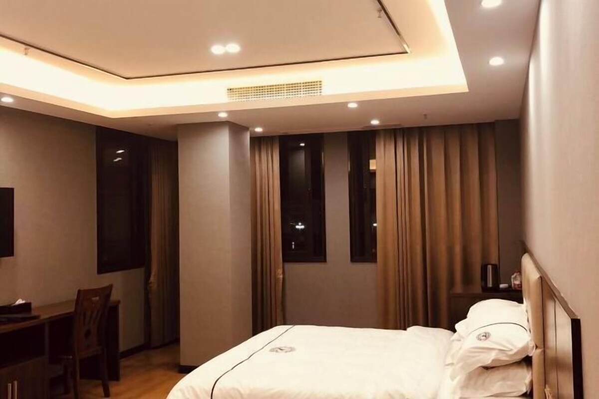 Quarto de hotel moderno com cama, escrivaninha e cadeira.