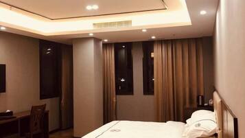 A modern hotel room with a bed, a desk, and a chair.