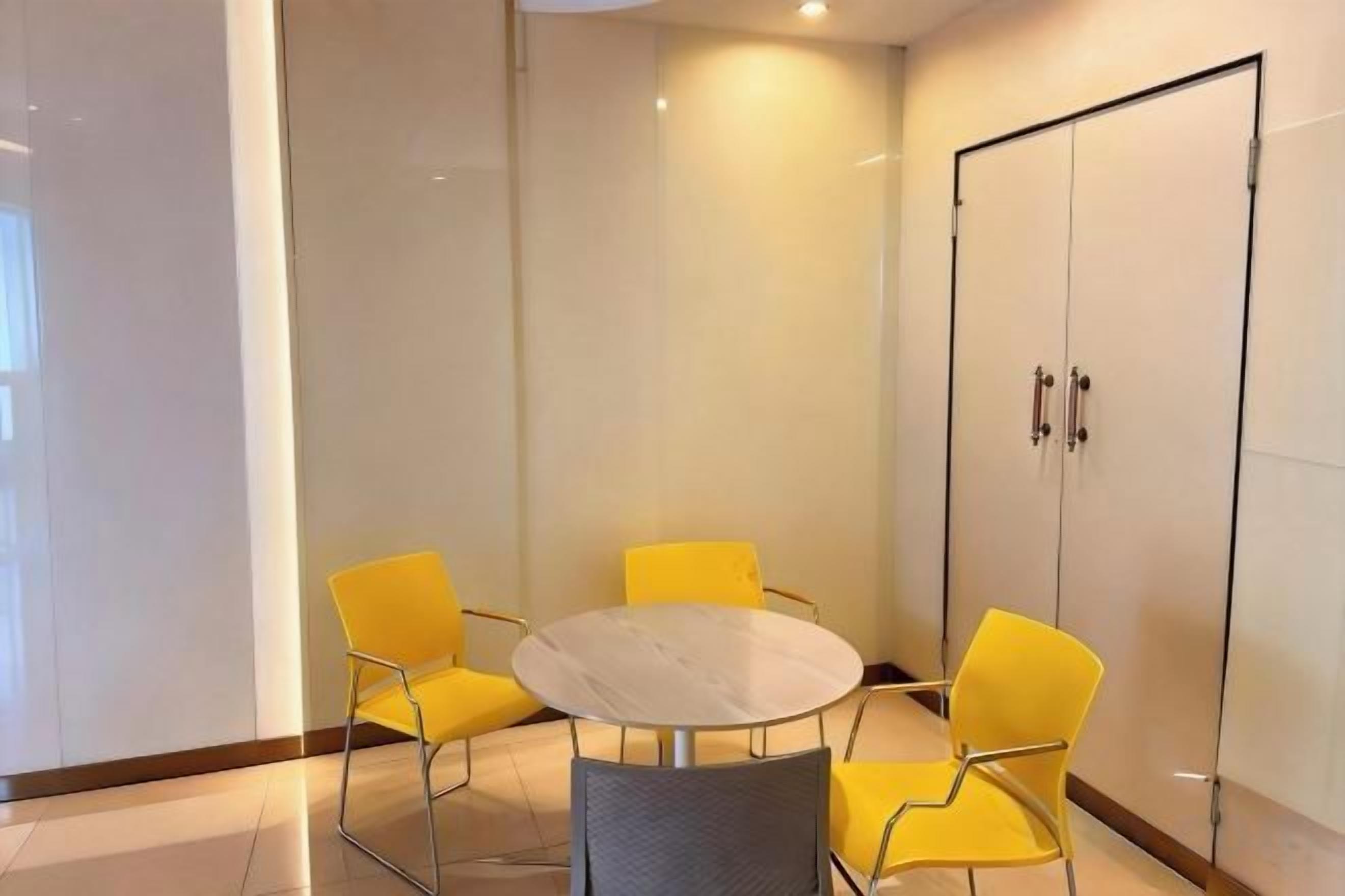 A conference room with a round table and four yellow chairs.