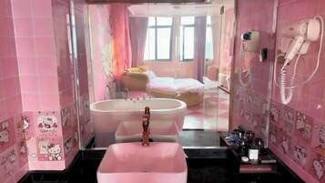 A pink-themed bathroom with a large sink, a hairdryer, and a mirror.