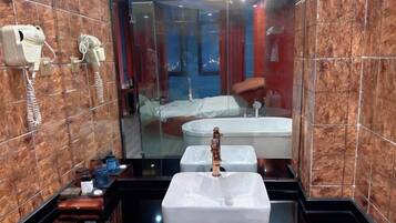 A modern bathroom with a large mirror, a white sink, a hairdryer, and a bathtub visible through the glass partition.
