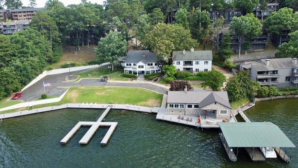 A lakeside property with a dock, a large house with a balcony, and a smaller building with a stone facade.