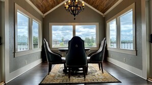 A dining area with a chandelier, large windows, and a view of a body of water.