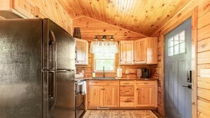 A compact kitchen with wooden cabinets, a black refrigerator, and a blue door.