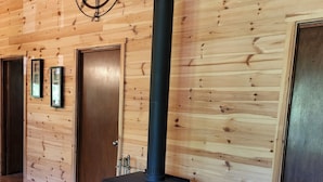 Un interior de madera con un estufa de leña negra, un adorno de pared con brújula y cuadros enmarcados.