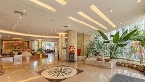 Un'ampia hall con pavimento lucido, un elemento decorativo centrale e una zona salotto.