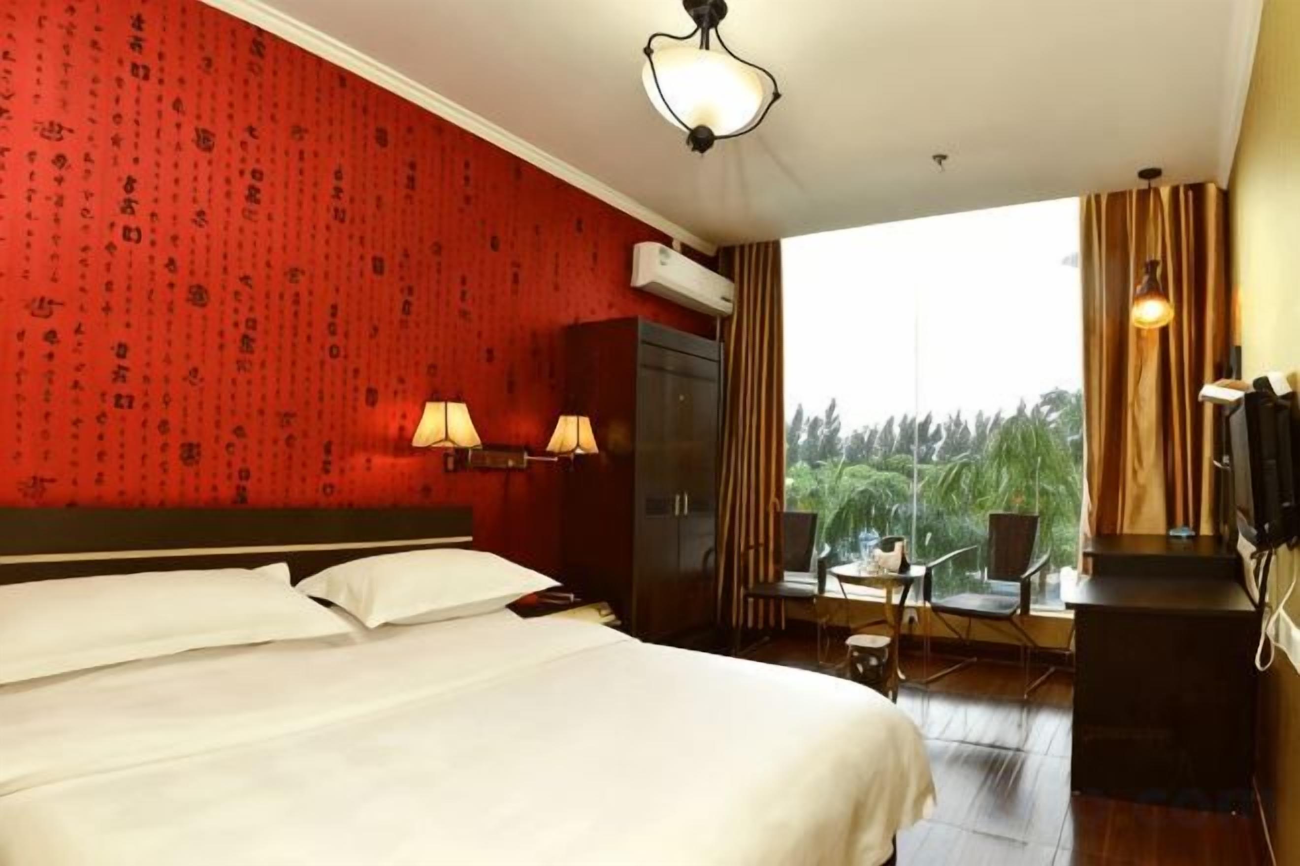 A hotel room with a large bed, two bedside lamps, a TV, and a view of the outdoors.
