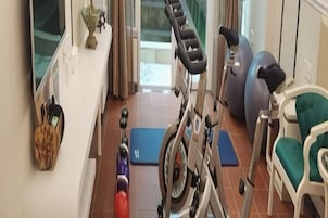 A home gym with exercise equipment, a yoga mat, and a chair.