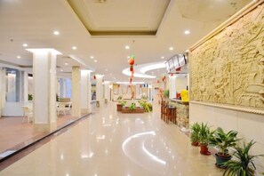 A hotel lobby with a polished floor, seating areas, and a decorative wall. - Huaxia Hotel (Dongshan County)
