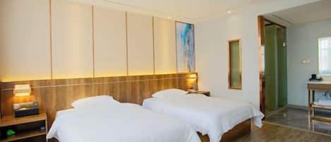 Une chambre d’hôtel avec deux lits, une tête de lit en bois, une table de chevet avec une lampe et un tableau au mur.