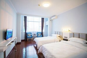 Une chambre d’hôtel avec deux lits, une télévision, un bureau, une chaise et une fenêtre avec des rideaux.