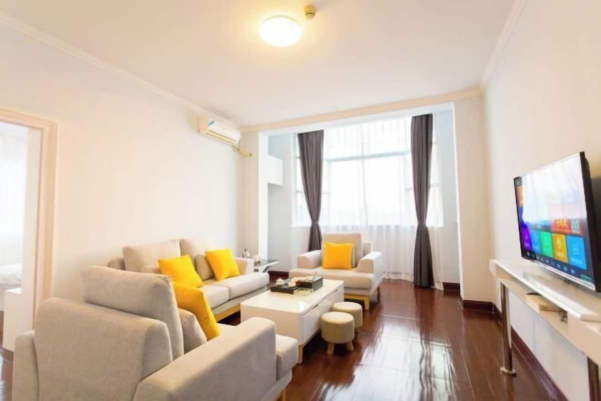 A modern living room with a sofa set, a coffee table, and a flat-screen TV.