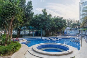 A swimming pool with a circular design, surrounded by greenery and a building in the background. - Huaxia Hotel (Dongshan County)