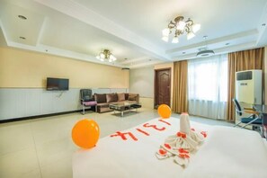 Une chambre d’hôtel avec un lit, un canapé, une télévision et un bureau.