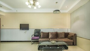 A living room with a sofa, a glass coffee table, a TV mounted on the wall, and a ceiling light fixture. - Duyun Jinpeng Hotel (Duyun Dashiban Ancient Street Store) (Duyun)