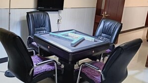 A conference room with a glass-top table, four black leather chairs, a flat-screen TV mounted on the wall, and a door in the background. - Duyun Jinpeng Hotel (Duyun Dashiban Ancient Street Store) (Duyun)