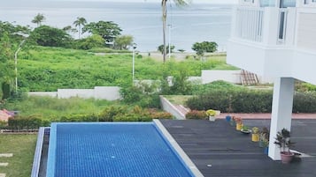 Enjoy a refreshing swim in the pool surrounded by lush greenery and ocean views.