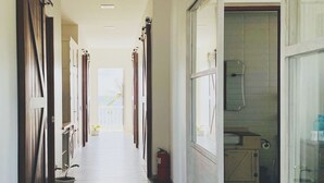 Un long couloir étroit, doté d’un plancher en bois, qui mène à une salle de bain avec une porte en verre.