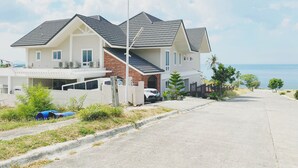 Une maison à deux étages avec un garage, une allée et une vue sur l’océan.
