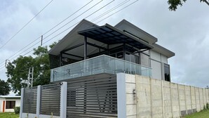 A modern house with a large balcony, a garage, and a concrete wall.