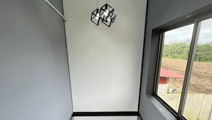 A modern staircase with a minimalist design, a geometric light fixture, and a view of an outdoor area through a large window.