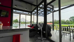 A modern room with a large window, a small pool, and a seating area with a fan.
