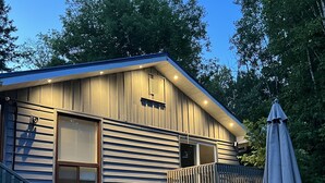 Eine Holzblockhütte mit einer Terrasse, Sitzgelegenheiten im Freien und einem überdachten Patio.