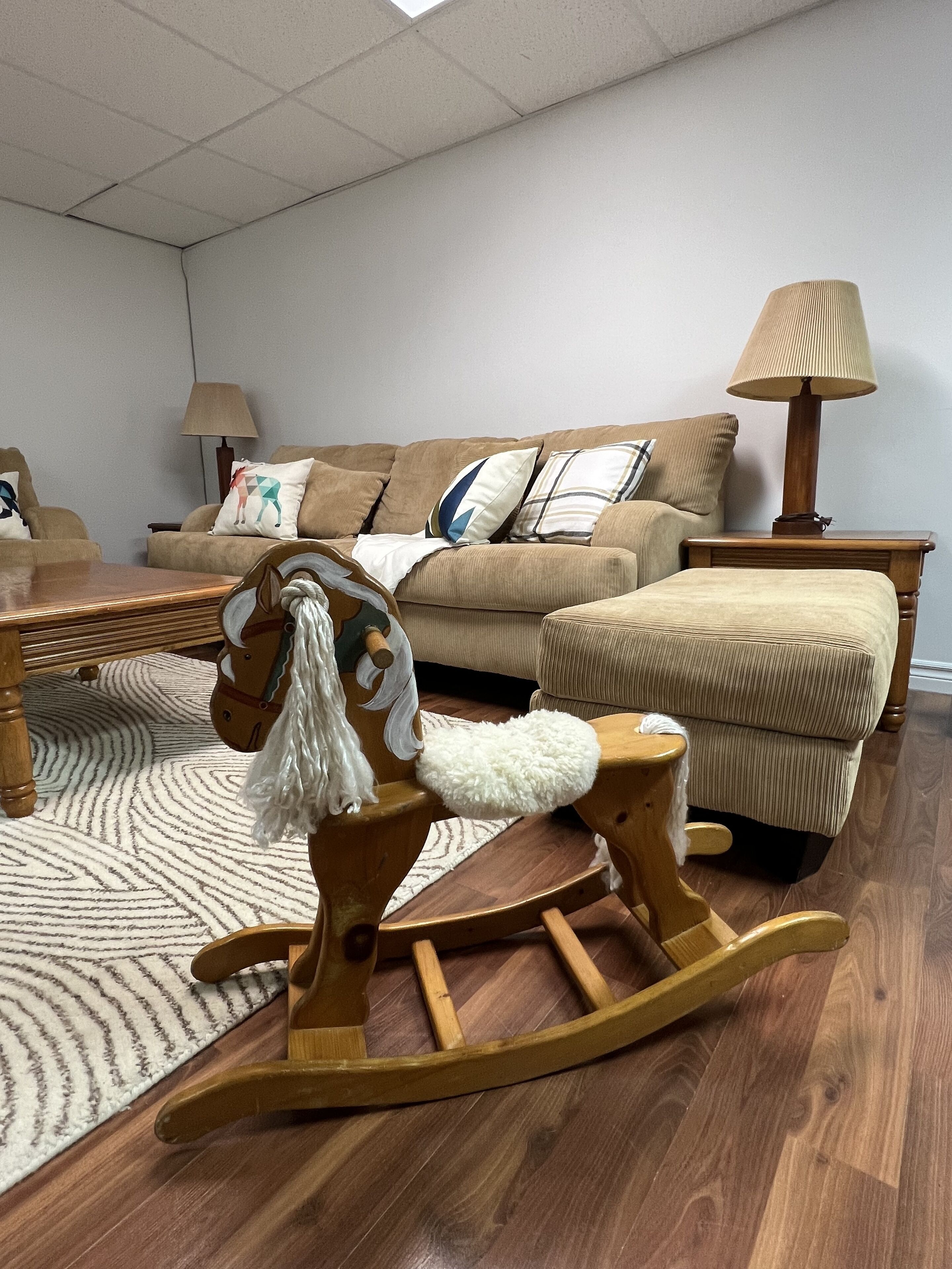 Un salon avec un cheval à bascule, un canapé, une table basse et une lampe.
