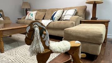 Un salon avec un cheval à bascule, un canapé, une table basse et une lampe.