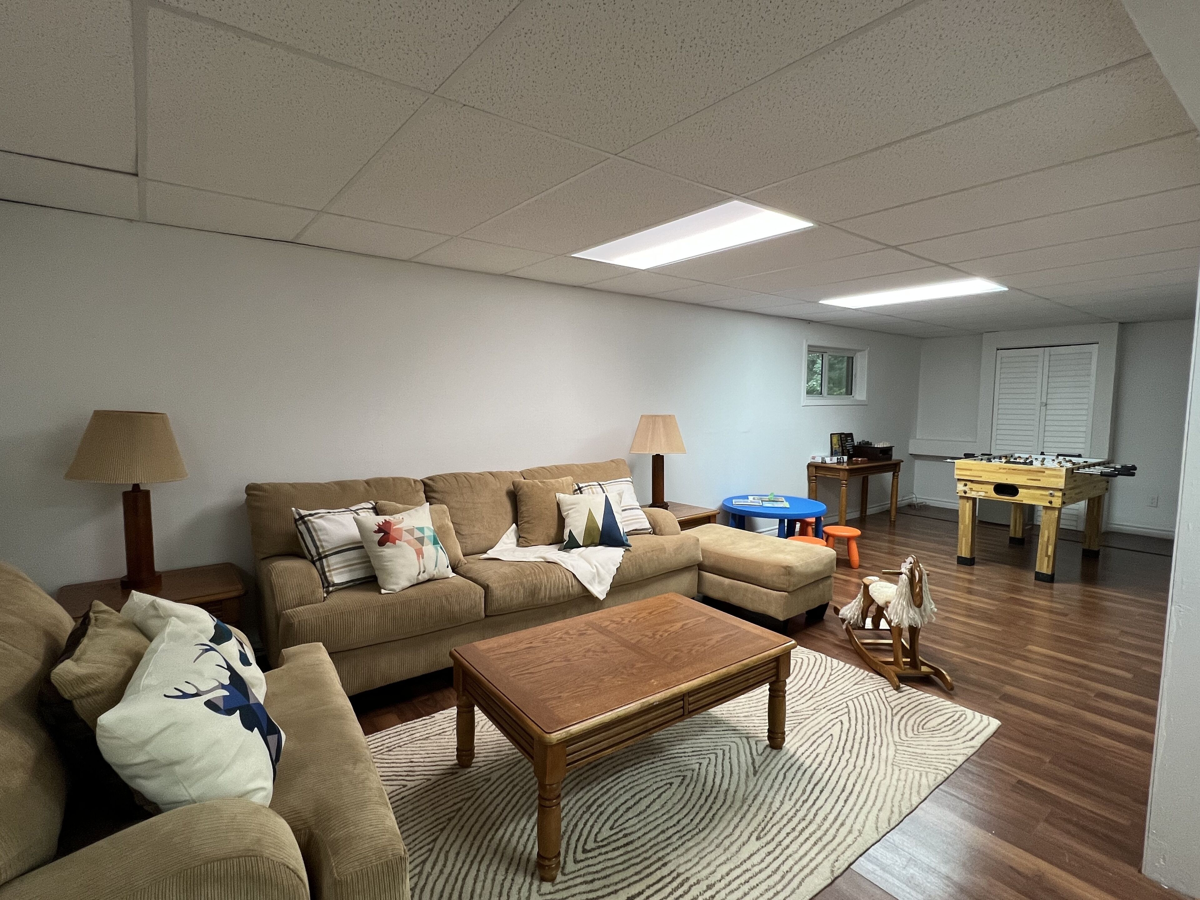 A living room with a sofa set, coffee table, lamps, and a foosball table.