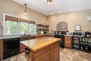 A spacious kitchen with a large island, granite countertops, and a stone backsplash. - Rustic Retreat by Taylor Made Deep Creek (Swanton)