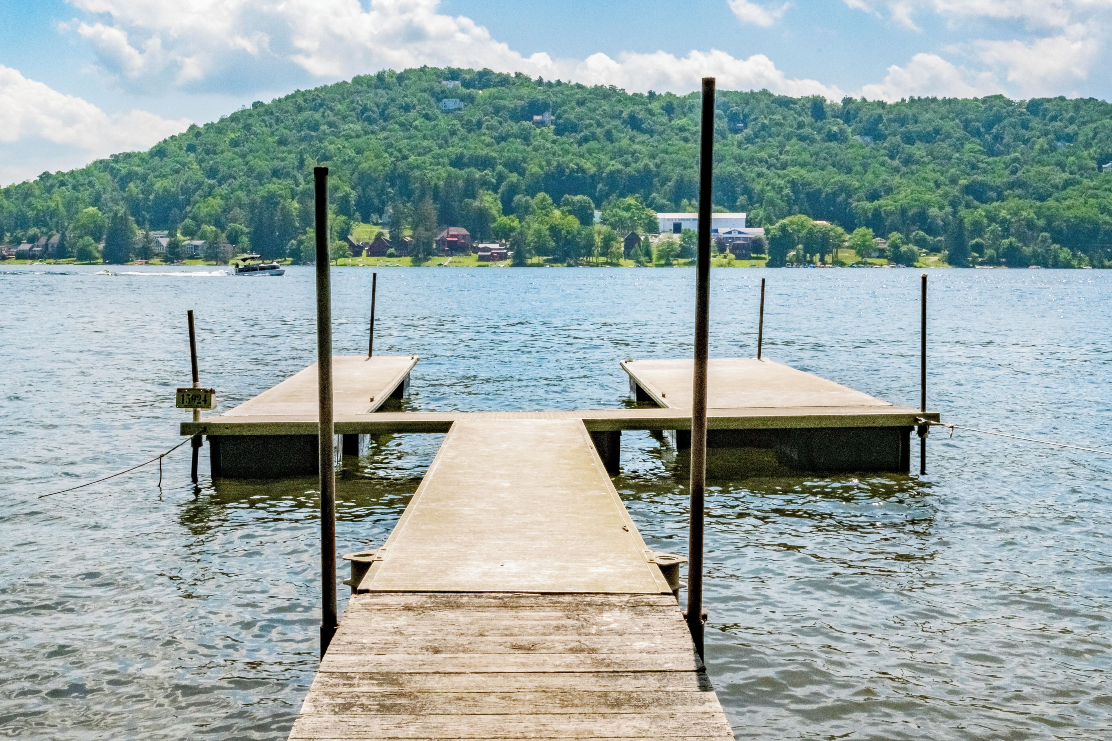 A wooden pier extending into a lake with a forested hill in the background.