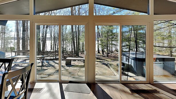 Habitación con ventanas amplias que ofrecen vistas a un área boscosa y una mesa de picnic en el exterior.