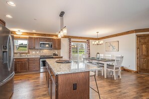 A modern kitchen with granite countertops, stainless steel appliances, and a wooden island. - Happy Ours by Taylor Made Deep Creek (McHenry)
