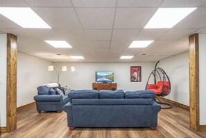 Uma sala de estar moderna com um sofá seccional, piso de madeira e uma cadeira suspensa.