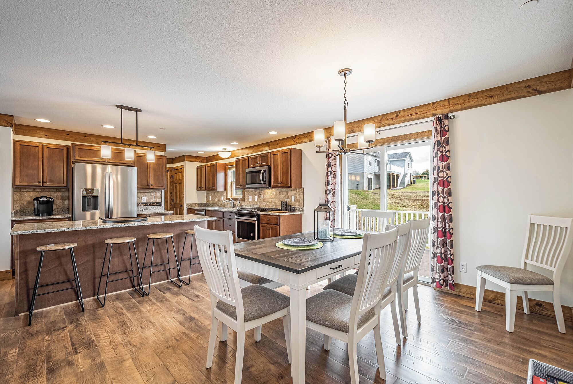 A modern kitchen with wooden cabinets, stainless steel appliances, and a bar area with stools.