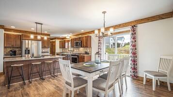 A modern kitchen with wooden cabinets, stainless steel appliances, and a bar area with stools.