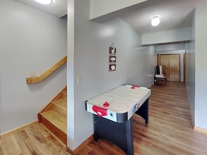 Ein Flur mit Holzboden, einem Tisch mit Pingpongnetz, einer Holztür und einer Treppe.