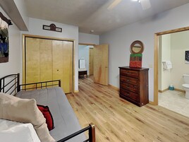 Una habitación con una cama, un aparador, un espejo y una puerta que da a otra estancia.