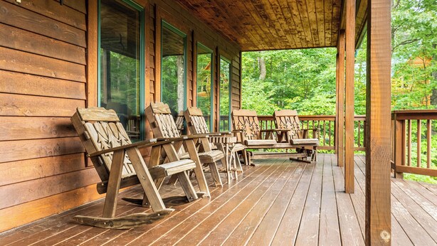 A wooden deck with rocking chairs and a table, overlooking a forested area. - Fairway Breeze by Taylor Made Deep Creek (McHenry)