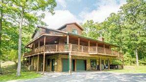 A two-story log cabin with a balcony, surrounded by trees. - Fairway Breeze by Taylor Made Deep Creek (McHenry)
